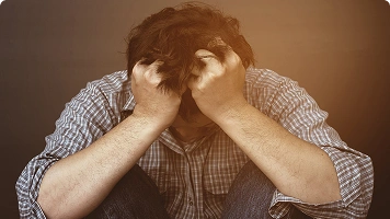 A woman wearing a pink top holding her hand over her face, appearing emotionally or physically exhausted.