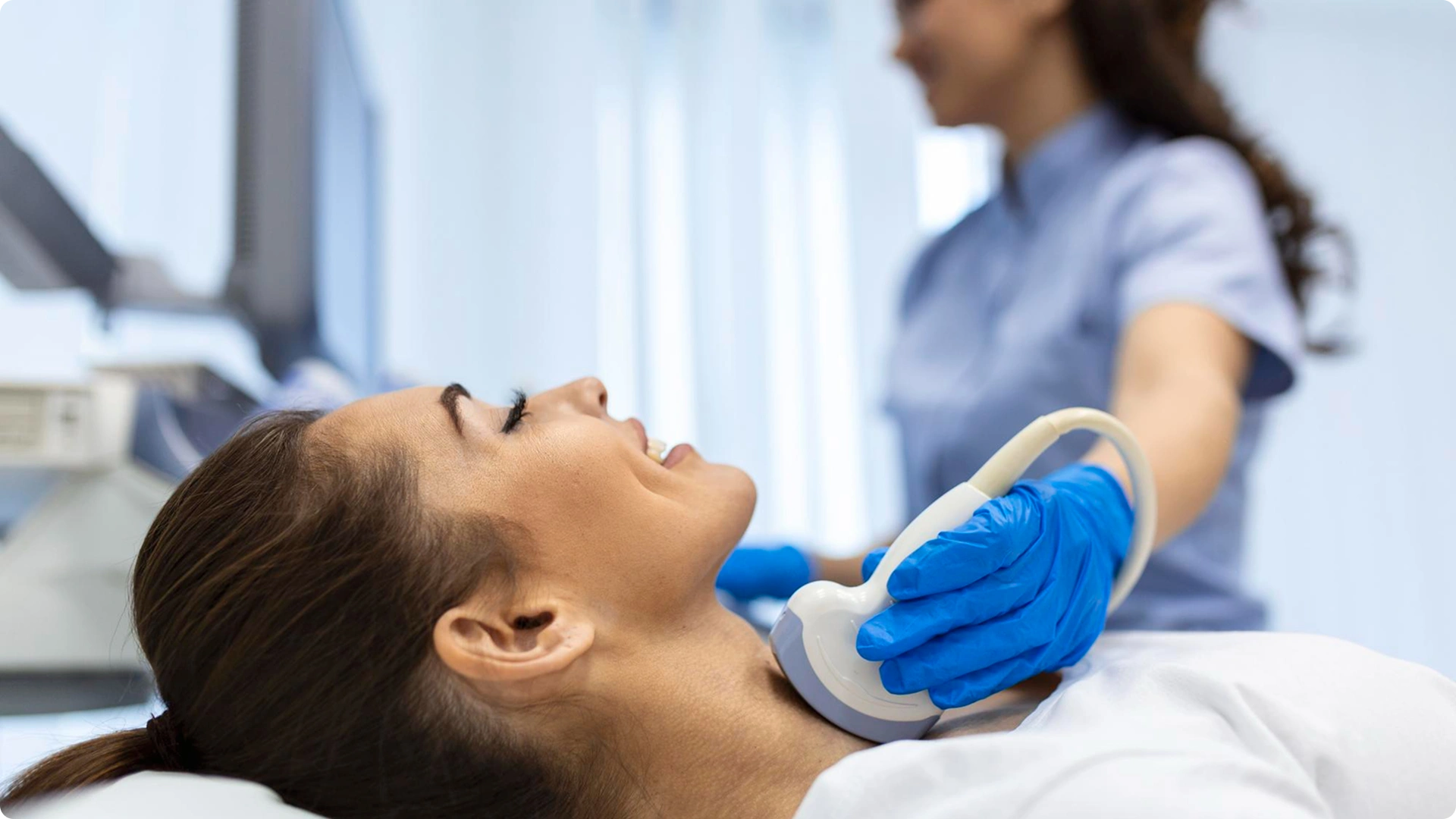 Doctor performing a thyroid ultrasound on a woman’s neck.