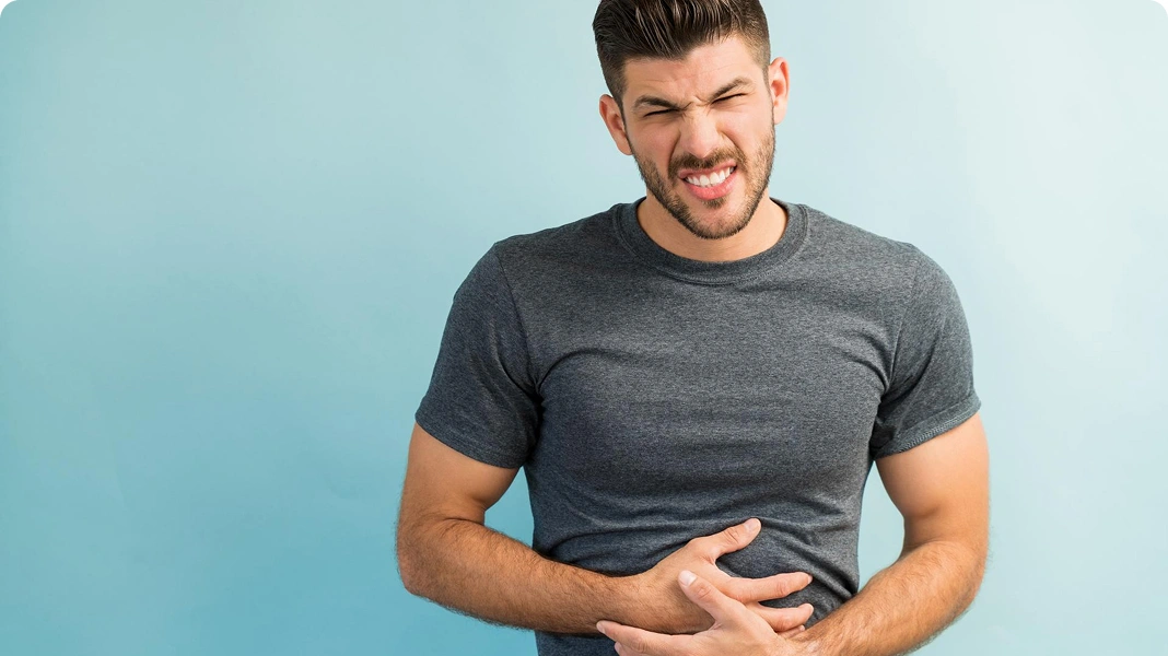 Man lying on couch holding stomach in pain.