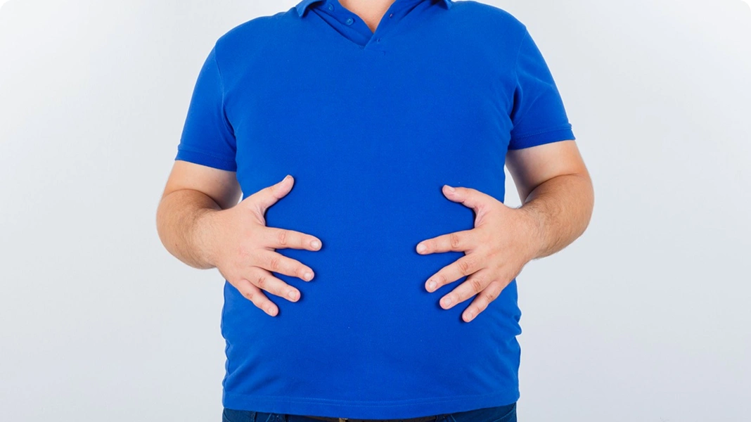 Man holding swollen abdomen.